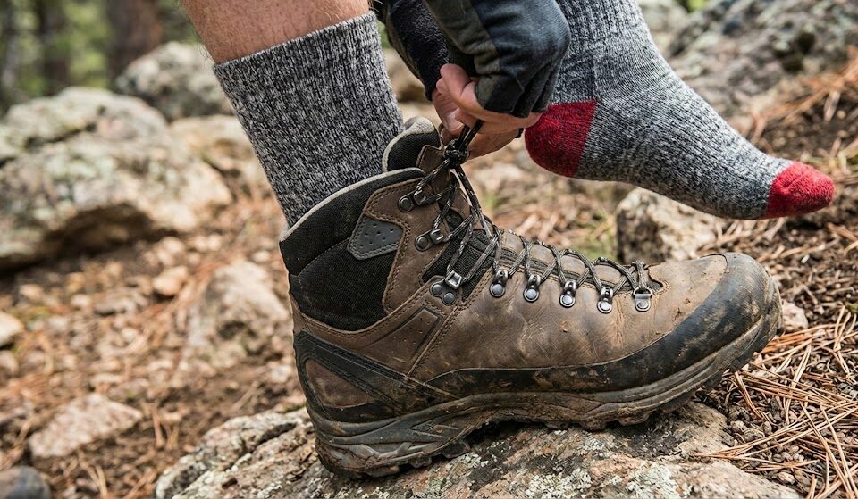 Bliższe ujęcie turysty wiążącego buty na szlaku. Widoczny nowoczesny system sznurowania.