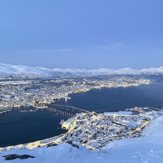 Panoramiczne ujęcie Tromsø nocą z punktu widokowego na górze Storsteinen.