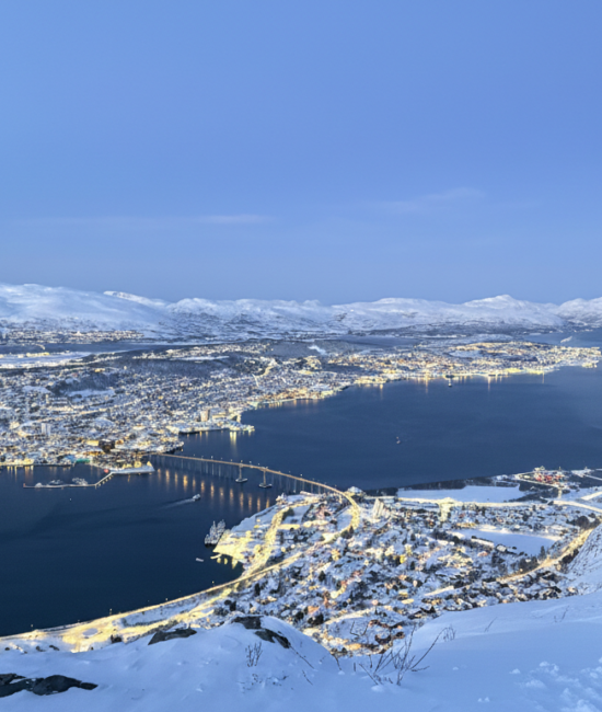 Panoramiczne ujęcie Tromsø nocą z punktu widokowego na górze Storsteinen.