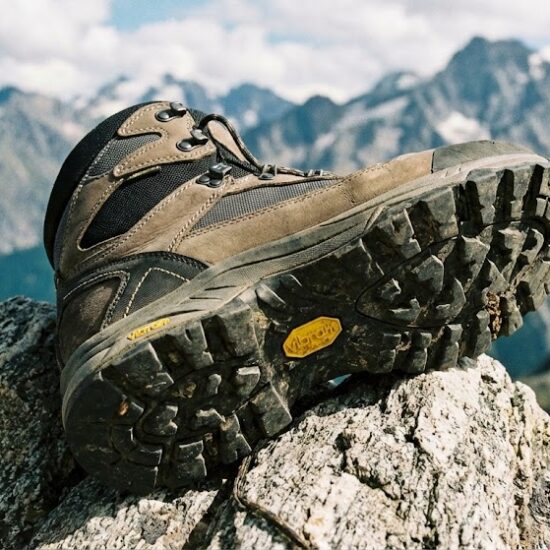 Profesjonalne zbliżenie na nowoczesny but trekkingowy postawiony na ostrej skale.