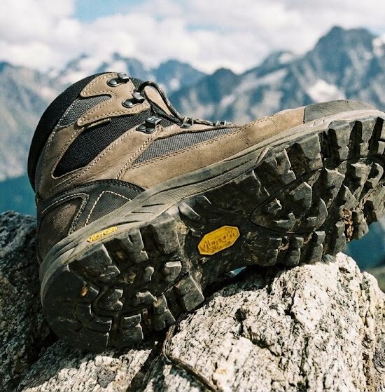 Profesjonalne zbliżenie na nowoczesny but trekkingowy postawiony na ostrej skale.
