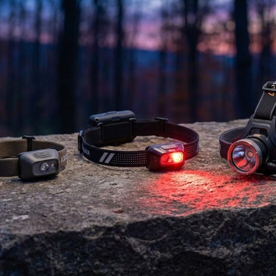 Profesjonalne zdjęcie produktowe przedstawiające trzy różne modele czołówek (kompaktową, biegową i wysokogórską) ułożone na surowym kamieniu.