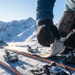 Zbliżenie na proces nakładania fok na narty skiturowe w mroźny, słoneczny poranek.