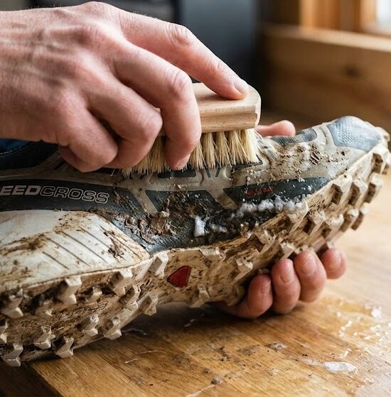 Zbliżenie na proces ręcznego czyszczenia buta biegowego po zimowym treningu