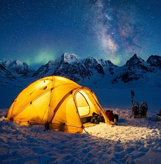 Zdjęcie namiotu ekspedycyjnego rozbitego na śniegu w samym sercu gór.
