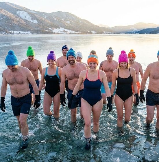 Zdjęcie przedstawiające grupę uśmiechniętych osób w kolorowych czapkach i rękawiczkach, wychodzących zdecydowanym krokiem do krystalicznie czystego