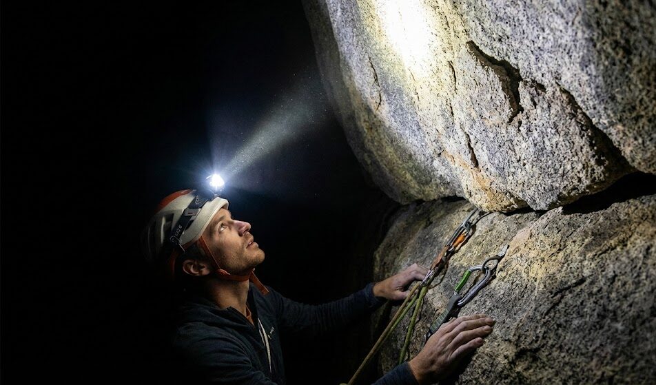 Zdjęcie turysty w kasku wspinaczkowym, na którym zamontowana jest czołówka.