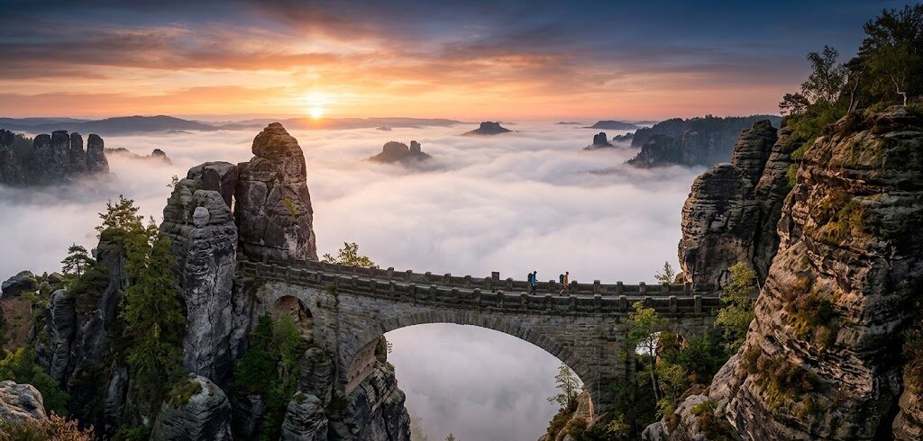 Epickie ujęcie słynnego kamiennego mostu Bastei (Basteibrücke) w Saksońskiej Szwajcarii o wschodzie słońca